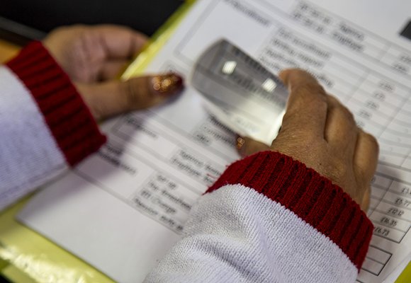 Close up of a person's hands using a magnifier on a sheet a paper.
