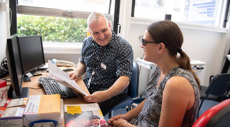 Mark Chapman in Luton hospital sat with a patient with sight loss.