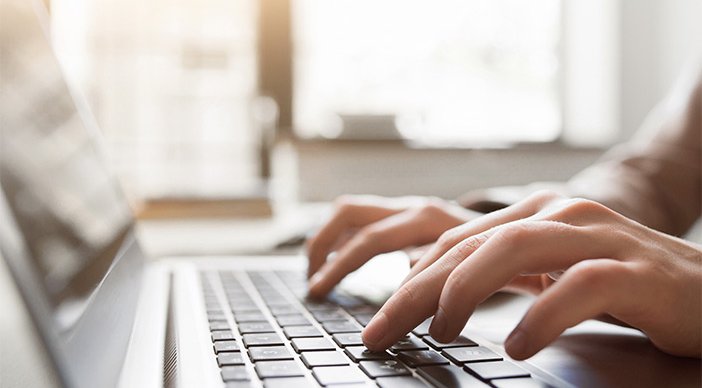 A closeup of hands as they type on a laptop keyboard, showing how you can stay at home by volunteering remotely for RNIB.