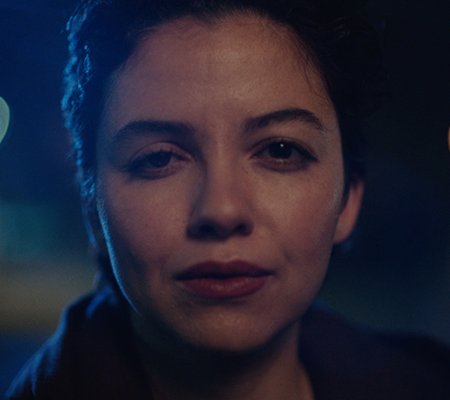 Ava's face close up at night outside, lit up by the street lights.