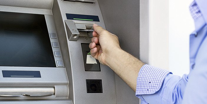 A man inserting a bank card into a cashpoint machine.