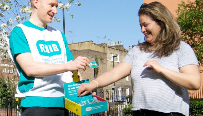 Volunteer fundraisers smile while collecting donations.