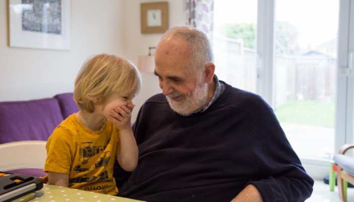 A man and child smiling together while sitting at a desk