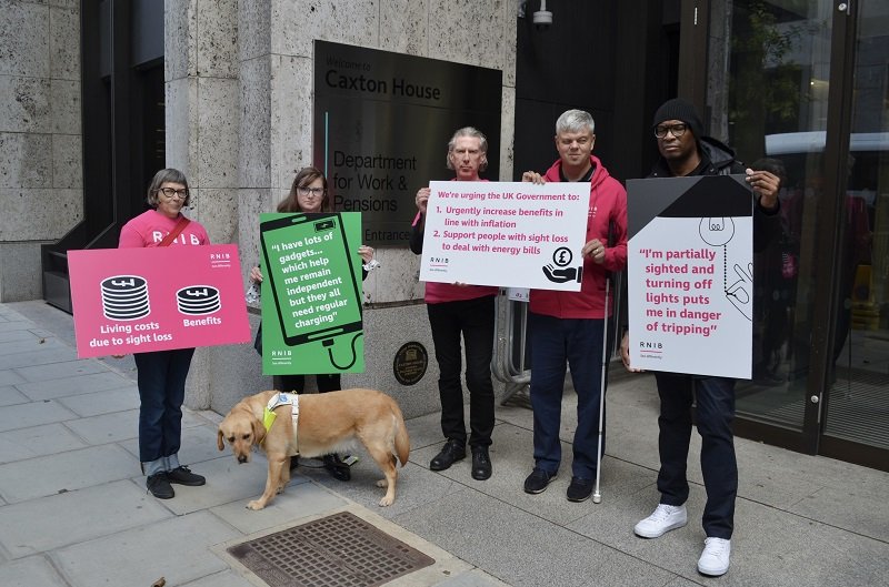 Group of RNIB campaigners campaigning outside holding boards.