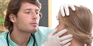 A health care professional wearing gloves and examining a young woman’s eyes.