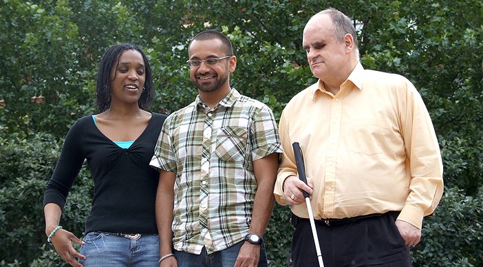 Image of three people with sight loss, one holding a white cane.