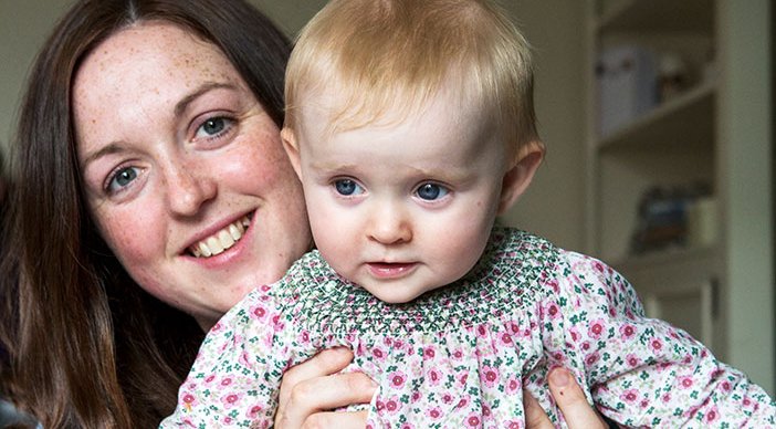 A mother holding baby and smiling.