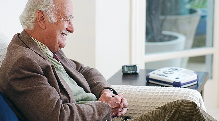 An older man sitting on a sofa and smiling
