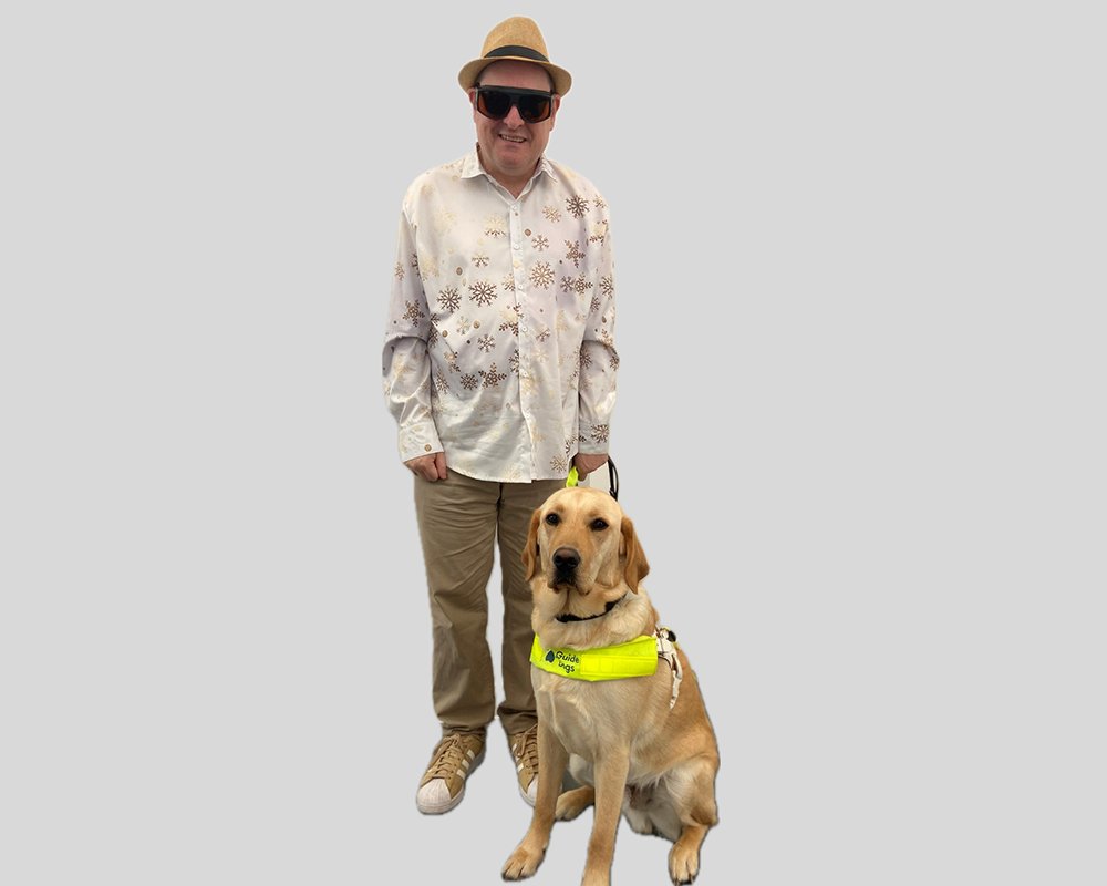 Photo of Paul and Stevie (Paul is wearing a straw trilby and dark glasses, Stevie is his guide dog)