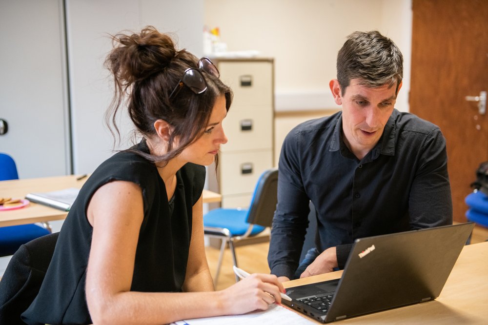 Two carers sitting together and looking attentively at a laptop.