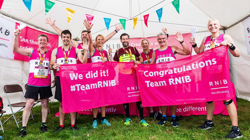 Seven RNIB Runners grouped together holding the congratulations and "we did it" banners