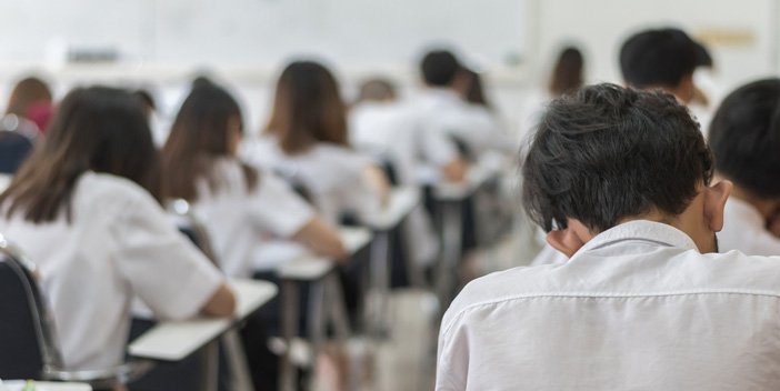 Rows of students sitting at tables, doing an exam.