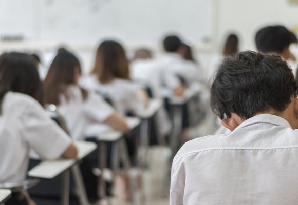 Rows of students sitting at tables, doing an exam.