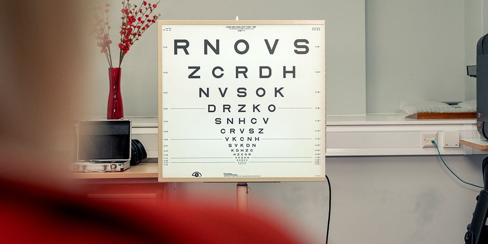 A Snellen chart used for eye tests viewed over a person's shoulder.