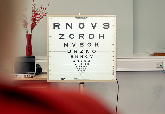 A Snellen chart used for eye tests viewed over a person's shoulder.