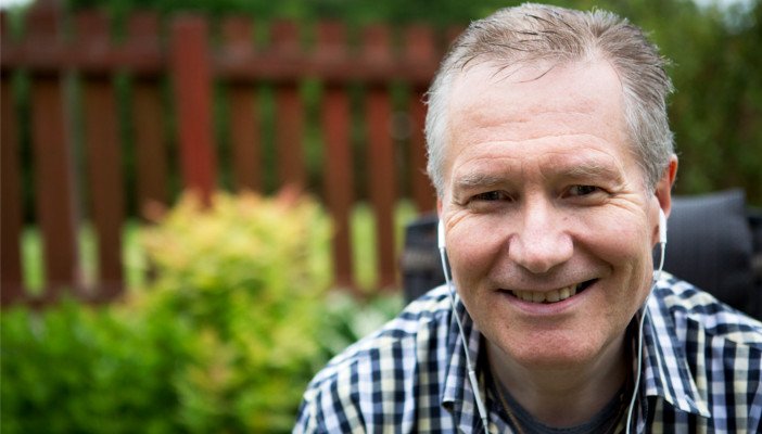 Middle-aged smiling man, wearing earphones in his garden
