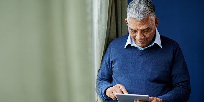 An older man consults a tablet computer