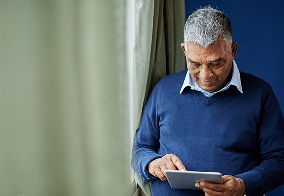 An older man consults a tablet computer