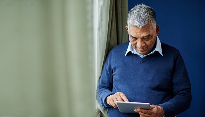An older man consults a tablet computer