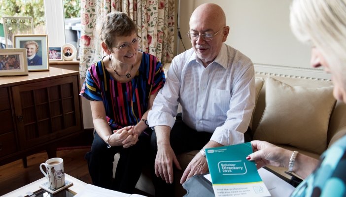 Jim and Mary sitting on a sofa at a coffee table with a Will advisor.