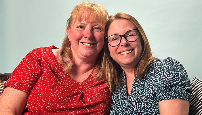 Two women with their arms round each other smiling at the camera