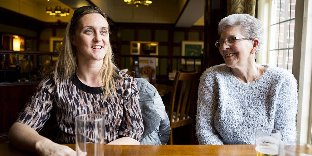 Two ladies sitting at a table in a pub enjoying a conversation.