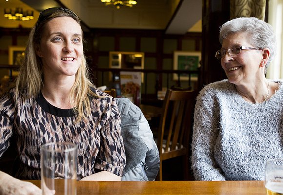 Two ladies sitting at a table in a pub enjoying a conversation.