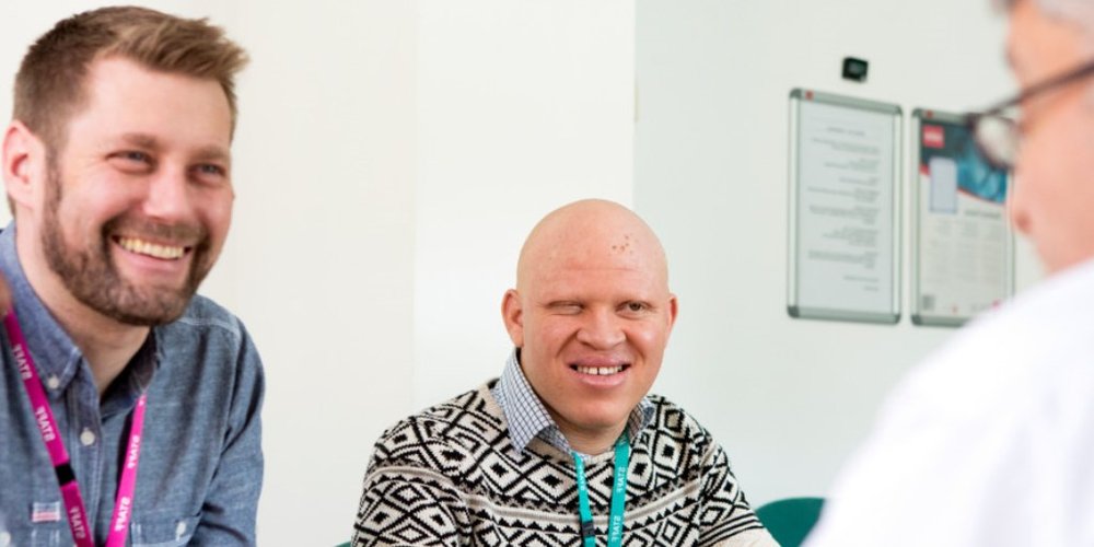 Two RNIB staff members sat talking to another person while smiling