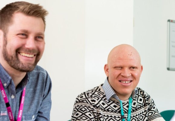 Two RNIB staff members sat talking to another person while smiling