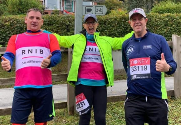 Three people wearing RNIB branded tshirts in pink and running labels.