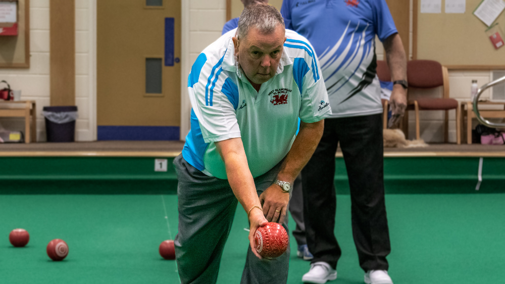 A man bent down about to throw a bowl
