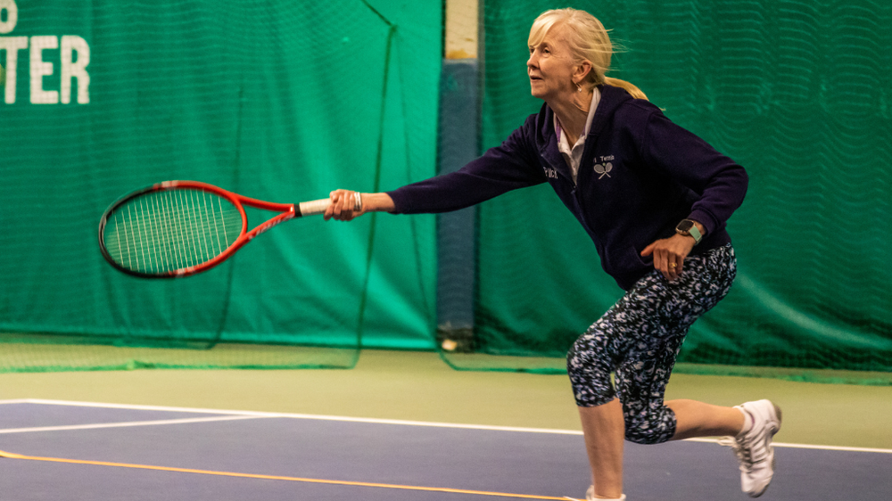 A woman holding a tennis racket on an indoor tennis court