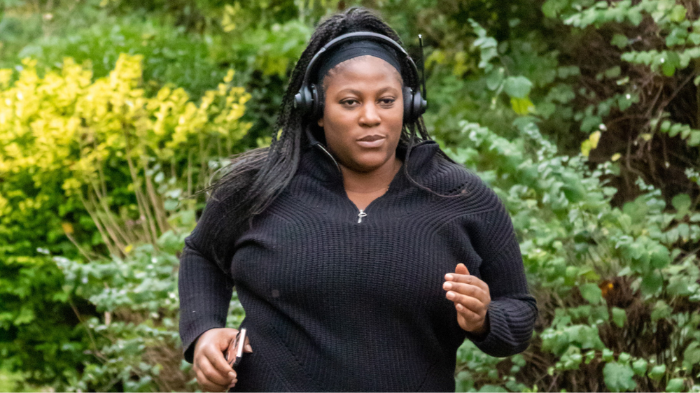 A woman running on a path in a park with headphones