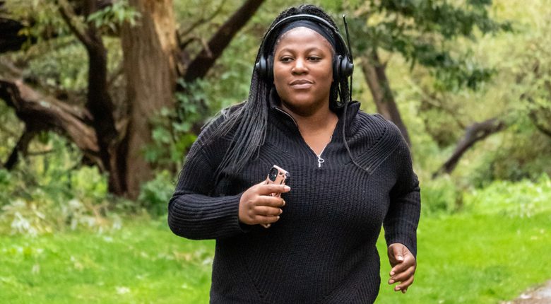 A woman running on a path in a park with headphones